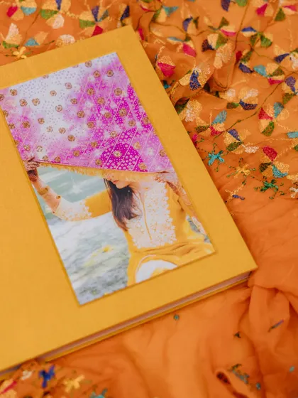 A close-up of a custom-made luxury wedding album, showcasing its yellow fabric cover and an inset photo.