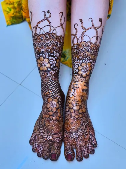 Intricate floral patterns on the bride's feet, designed to match the henna on her hands. The detail extends to every toe.