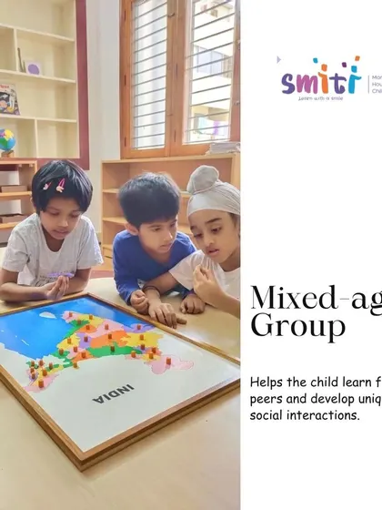 In our mixed-age classrooms, older children often become mentors to their younger peers. Here, a group of children collaborates on a puzzle map of India, learning geography and social skills together.
