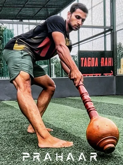 This image, labeled PRAHAAR, shows an athlete in a powerful stance with the Gada. It represents our core training program, designed to correct posture, analyze movement, and build strength for all fitness levels using traditional Indian equipment.