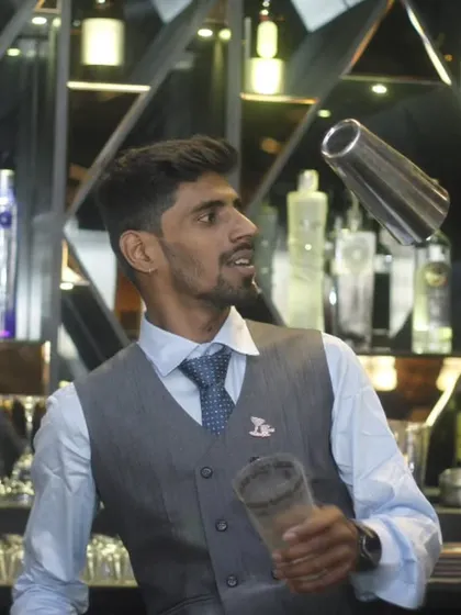 A flair bartender in his element, effortlessly tossing a shaker. This is the kind of entertainment and skill that elevates a standard bar service into a memorable performance.