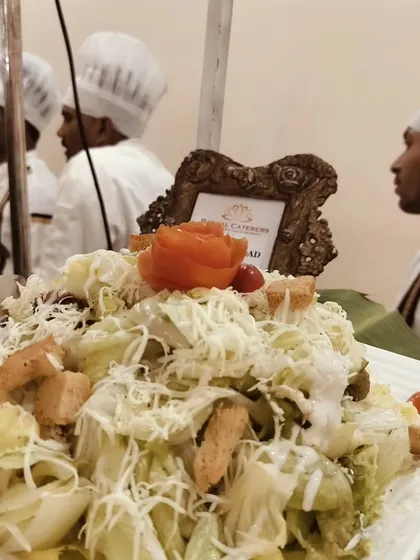 My Caesar salad, generously topped with parmesan cheese and croutons, with my team of chefs reflected in the background.