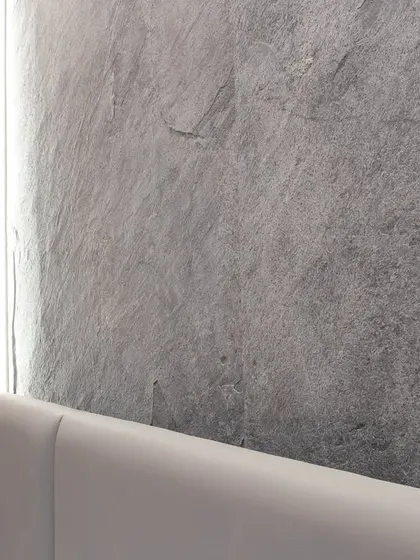 A close-up of the thin-cut granite slab used as a feature wall. Framed by soft ambient lighting, this natural material brings a sense of quiet grandeur and texture to the room.