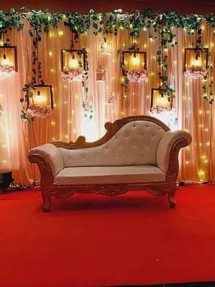 An elegant stage for a ring ceremony or reception. This design features a backdrop of soft drapes and fairy lights, with beautiful hanging lanterns and a classic chaise lounge, creating a warm and romantic ambiance perfect for photographs.