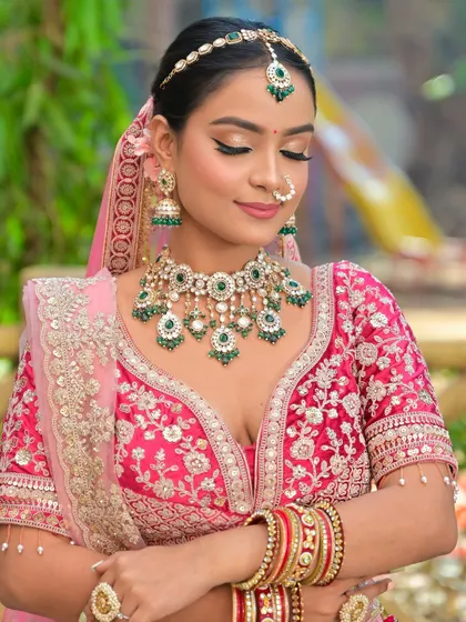A vibrant look featuring a stunning Kundan and green bead jewellery set against a bright pink lehenga. This combination is perfect for a bride who loves bold colors.