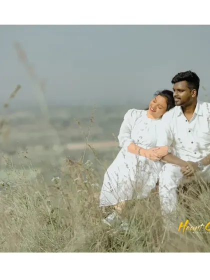 A couple relaxes in a sun-drenched field, sharing a happy and candid moment. The warm light creates a beautiful, golden glow.