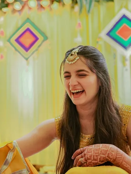 A candid moment of laughter during Archie's Haldi. Dressed in vibrant yellow, her genuine smile reflects the cheerful and celebratory atmosphere of the pre-wedding rituals.