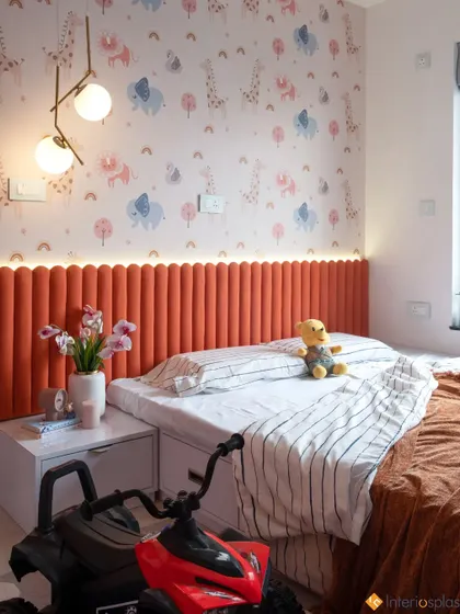 A full view of the kid's room, showing the orange fluted headboard with integrated LED lighting, the whimsical wallpaper, and plenty of space to play.