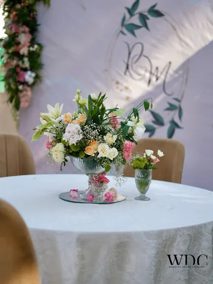 A tabletop centerpiece of delicate pastel flowers, set against a backdrop with the couple's custom monogram, adding a personal and elegant touch.
