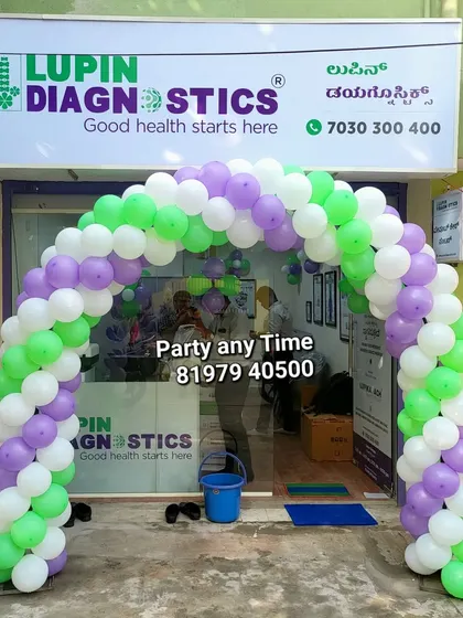 A balloon arch in purple, green, and white for the opening of a Lupin Diagnostics center.