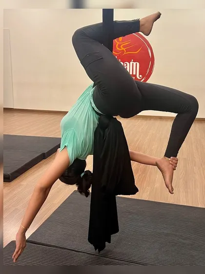 A different angle of the inverted scorpion pose in the aerial hammock. This view shows how the hammock supports the hips, allowing the spine to open up and release tension.