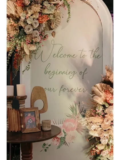 A welcome sign for the vow exchange, framed by beautiful arrangements of pampas grass and dried flowers.