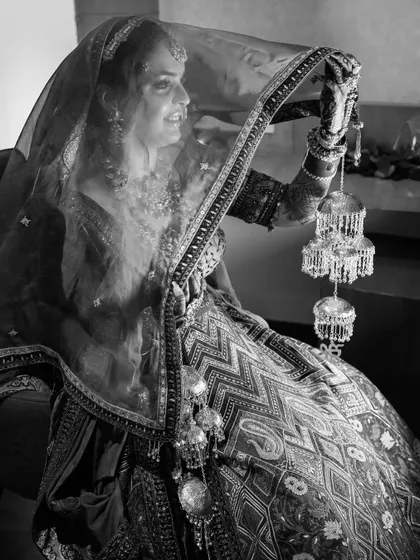 A candid black and white shot of the bride, holding her kalire. Her smile and the soft focus on the traditional bangles make for a beautiful, emotional image.