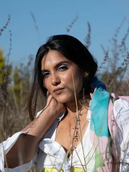 An outdoor shoot with a pop of blue eyeliner. The makeup is fresh and summery, designed to stand out against the natural background.