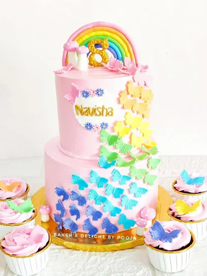 A flutter of magic for Navisha's 8th birthday. This two-tier pink cake features a cascade of rainbow-colored butterflies and was served with matching butterfly cupcakes.
