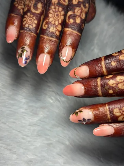 A delicate and modern bridal look. We did a soft peach ombre on her natural nails and added tiny, hand-painted floral stickers and a simple gold ring detail.