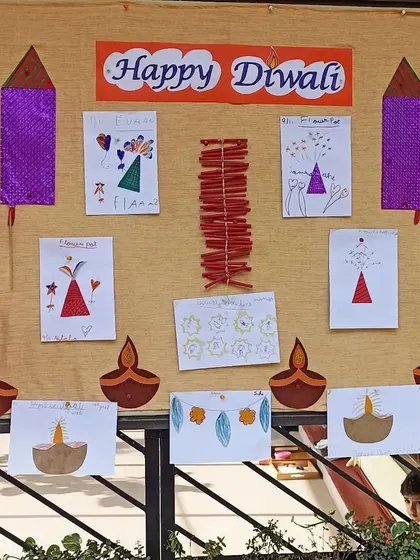 A display of children's Diwali artwork, including drawings of diyas and firecrackers.