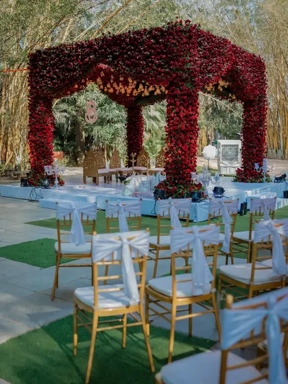 A stunning red floral mandap set against a lush green backdrop. We highlight the beauty of your wedding decor to create a vibrant visual story.
