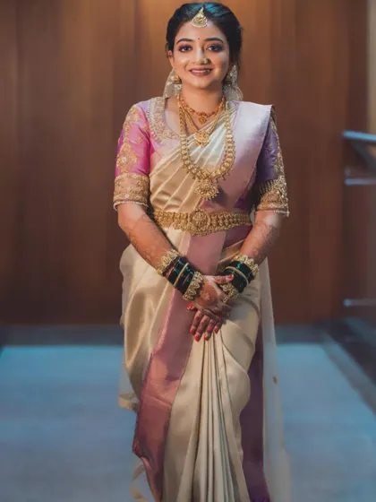 A full-length photo showing Aishwarya's complete bridal look, featuring a beautiful off-white and pink saree.