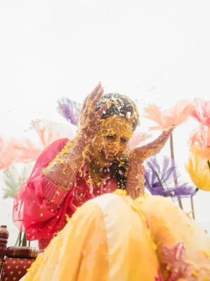 A shower of flower petals rains down on the bride. This action shot captures the festive and celebratory atmosphere of her dreamy, floral-themed haldi.
