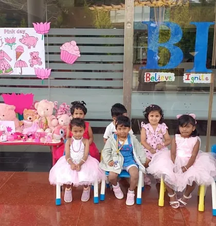 A group of our youngest learners sitting in front of the Pink Day display, surrounded by pink teddy bears and decorations.