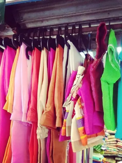 A selection of blouse pieces and fabrics hanging in my shop. I can help you find the perfect color and material for your next custom-stitched blouse.