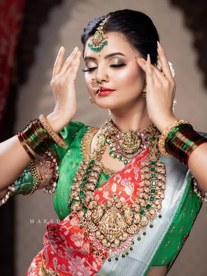 The rich textures of this bridal look are everything. The silk saree, the embroidered blouse, and the layers of temple jewelry come together to create a truly divine look.
