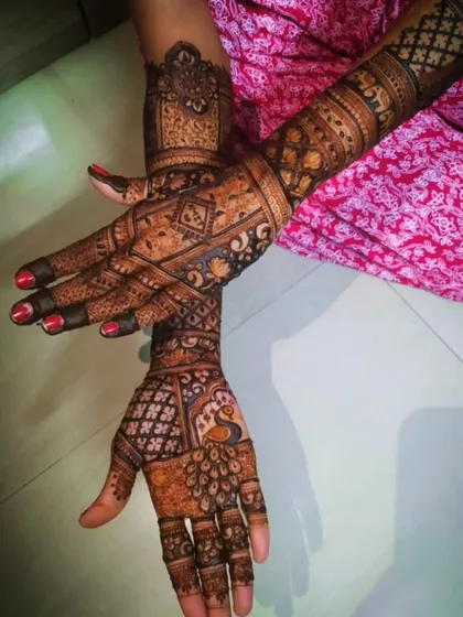 A bridal design that combines different traditional elements. One hand features a peacock, while the other has geometric block patterns, all tied together with similar wrist and finger designs.
