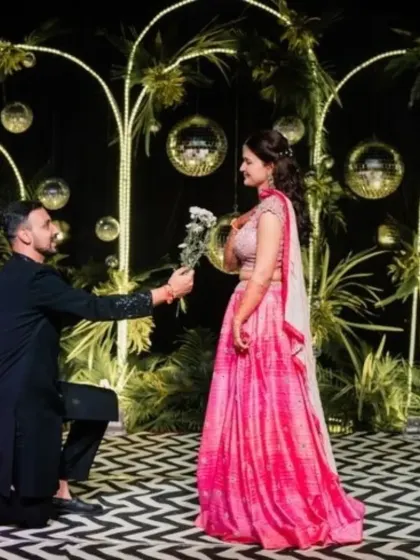 A romantic moment on the Sangeet stage. The backdrop of illuminated arches and disco balls creates a magical setting for couple performances and photos.