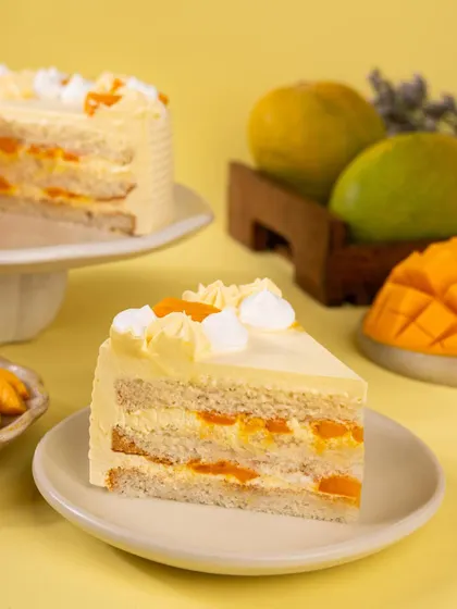 A slice of the mango cream cake, revealing the light sponge and fresh mango layers inside.