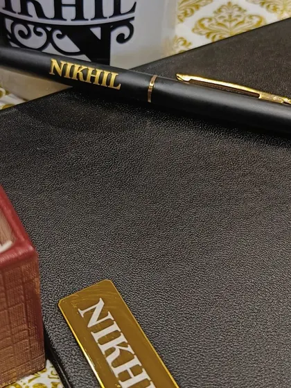A close-up of the personalized pen and diary with the name 'Nikhil' engraved in gold.