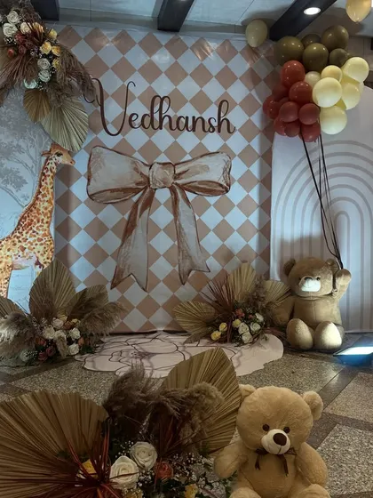 The full view of our boho-chic naming ceremony setup for Vedhansh. The design features a custom checkered backdrop, balloon arches in muted tones, and adorable teddy bears to create a soft, dreamy atmosphere.