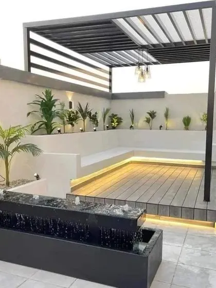 This modern patio features a sleek pergola, built-in white seating, and a tranquil water feature. It's a perfect blend of minimalist design and natural elements.