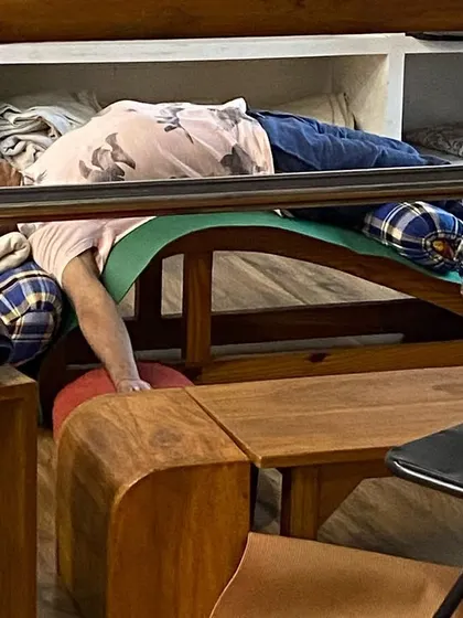 A student relaxing in a supported backbend on a curved bench. This prop is specifically designed to open the chest and support the natural curve of the spine.