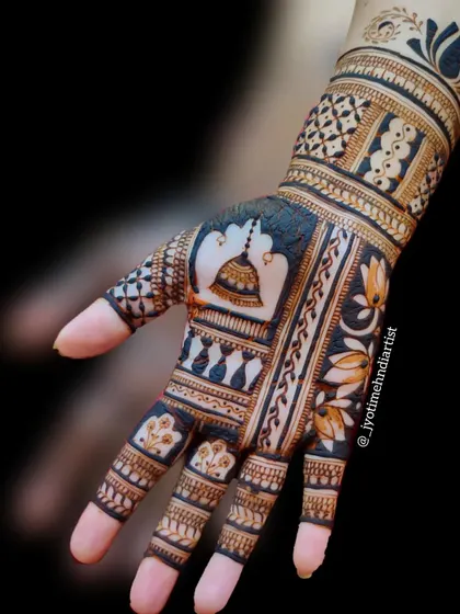 This designer henna piece showcases a prominent temple bell (ghanti) motif, combined with lotus flowers and geometric patterns for a unique, spiritual design.