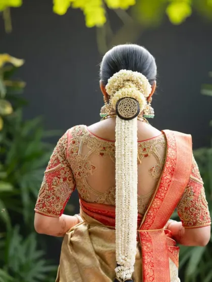 A detailed view of the blouse's back, showcasing the intricate embroidery and the beautiful cutout design on sheer net. Paired with a traditional jasmine braid, this look is the epitome of South Indian bridal beauty.