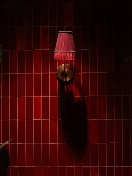 A close-up of the red wall tiles at Hikki. The way the light hits the glossy surface creates beautiful reflections and shadows, adding depth and texture to the wall. This simple detail demonstrates how the right tile and lighting can create a powerful mood.