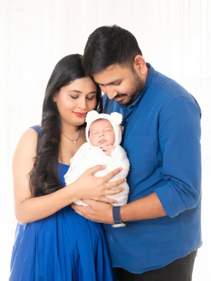 A peaceful family portrait, with mom and dad holding their sleeping newborn close.