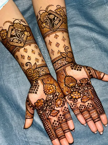 A gorgeous floral design that extends up the arm. The use of negative space with scattered motifs on the forearm contrasts beautifully with the denser patterns on the palm.