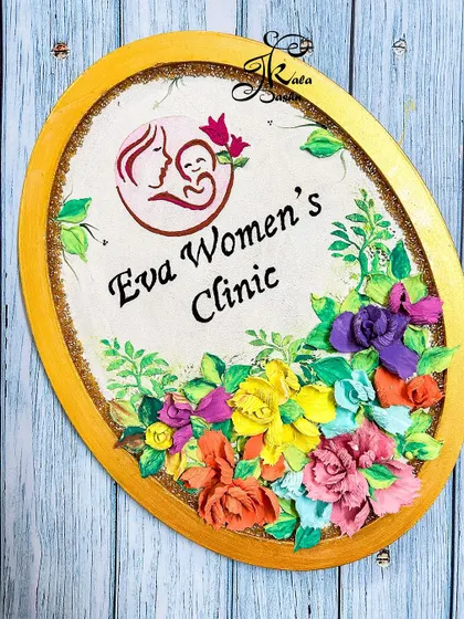 The full view of the "Eva Women's Clinic" nameplate, set against a wooden background to highlight its warm colors.