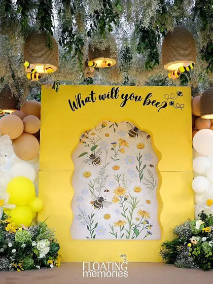 The main photo backdrop was a highlight of the event. A bright yellow wall with the question 'What will you bee?' featured a beautiful floral insert, framed by balloons, daisies, and hanging handmade beehives.