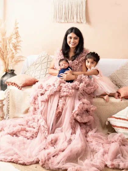 A stunning portrait of a mother with her newborn and older daughter, showcasing one of the beautiful gowns available in our studio.