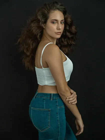 A clean and simple portrait with a focus on natural beauty. The movement in the hair adds a touch of life, while the dark background makes the subject stand out.