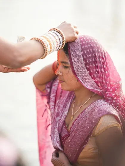 A woman receives a tilak on her forehead during the Chhath Puja rituals. These symbolic acts are an important part of the worship.