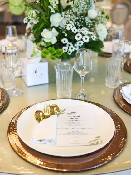A beautifully coordinated place setting featuring hammered copper charger plates and a custom-printed menu. These details demonstrate our commitment to creating a cohesive and branded dining experience for your event.