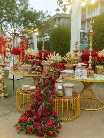 The food display is a feast for the eyes, with cascading red florals and golden decor elements creating a look of abundance and celebration.