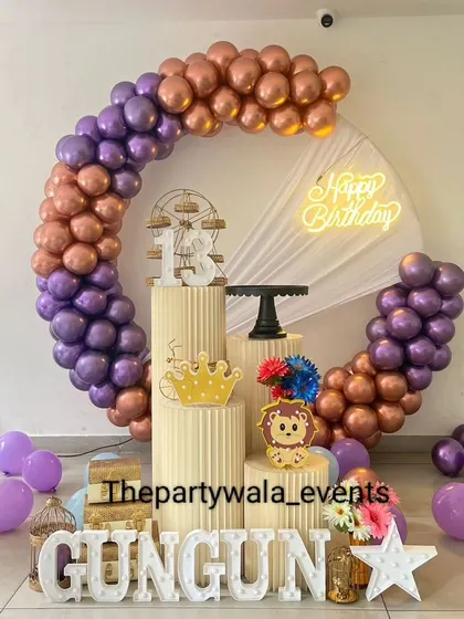 A purple and rose gold balloon ring with a 'Happy Birthday' neon sign and light-up letters.