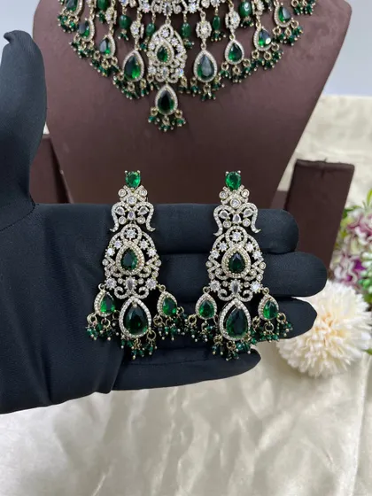 A heavy bridal choker set in a stunning emerald green. This design features multiple layers of stones and bead droppings, complete with matching oversized earrings, making it a comprehensive offering for your bridal customers.
