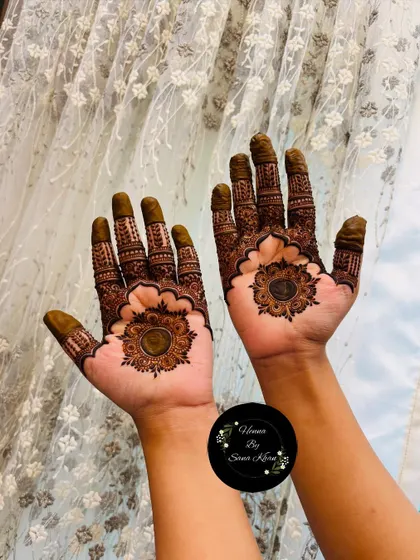 This design features a central mandala with a unique floral border. The fingers are heavily decorated, balancing the open space on the palm.