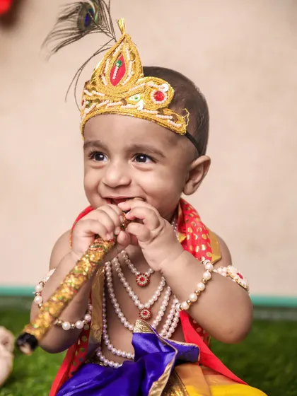 The pure joy of a child's smile is priceless. This little Krishna is captured in a moment of happiness, holding his flute, creating a heartwarming and candid portrait.